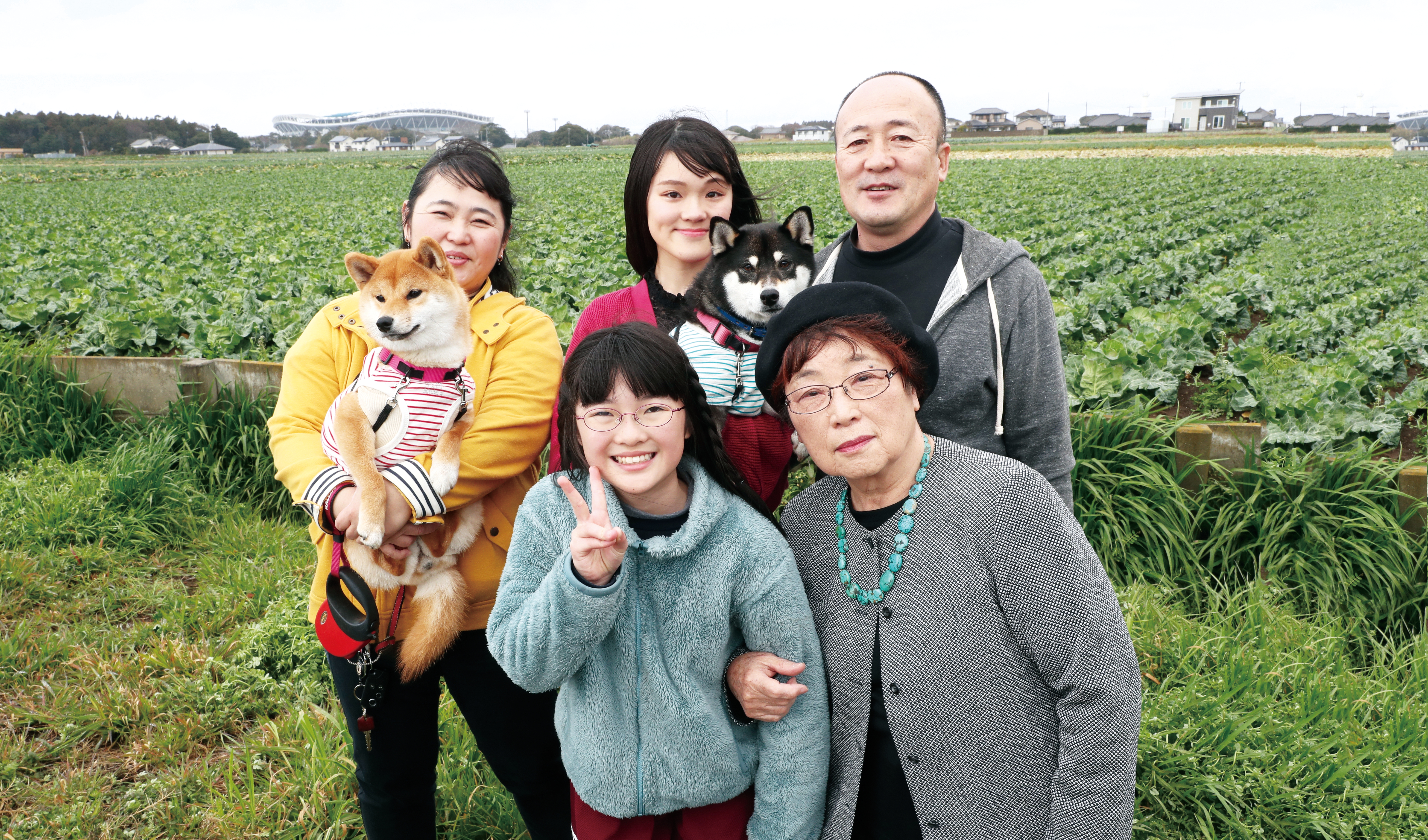 二匹の愛犬と一緒に。鹿嶋特産の汐菜キャベツ畑越しに カシマサッカースタジアムが見える。