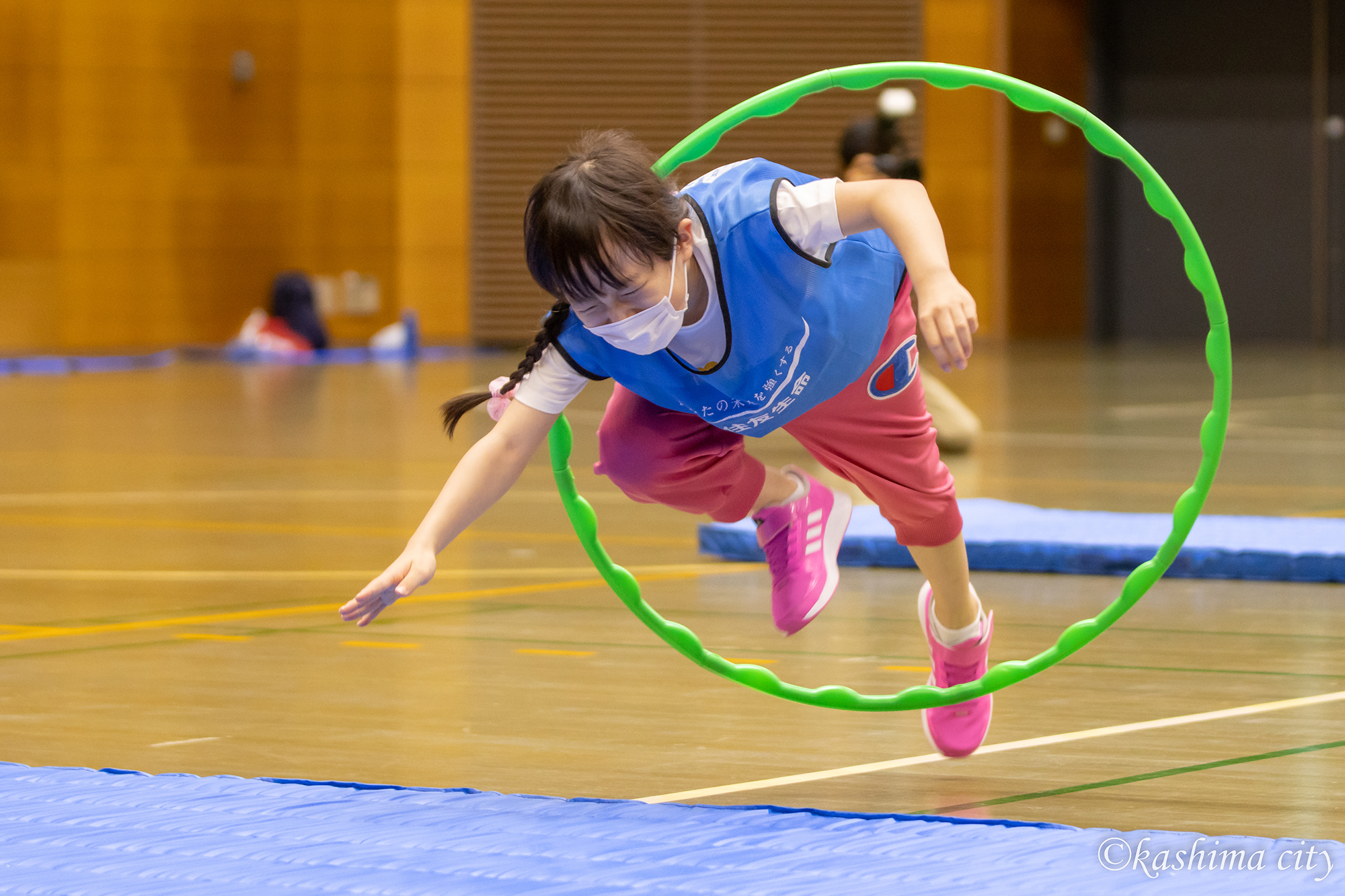 フラフープにジャンプして飛び込む女の子