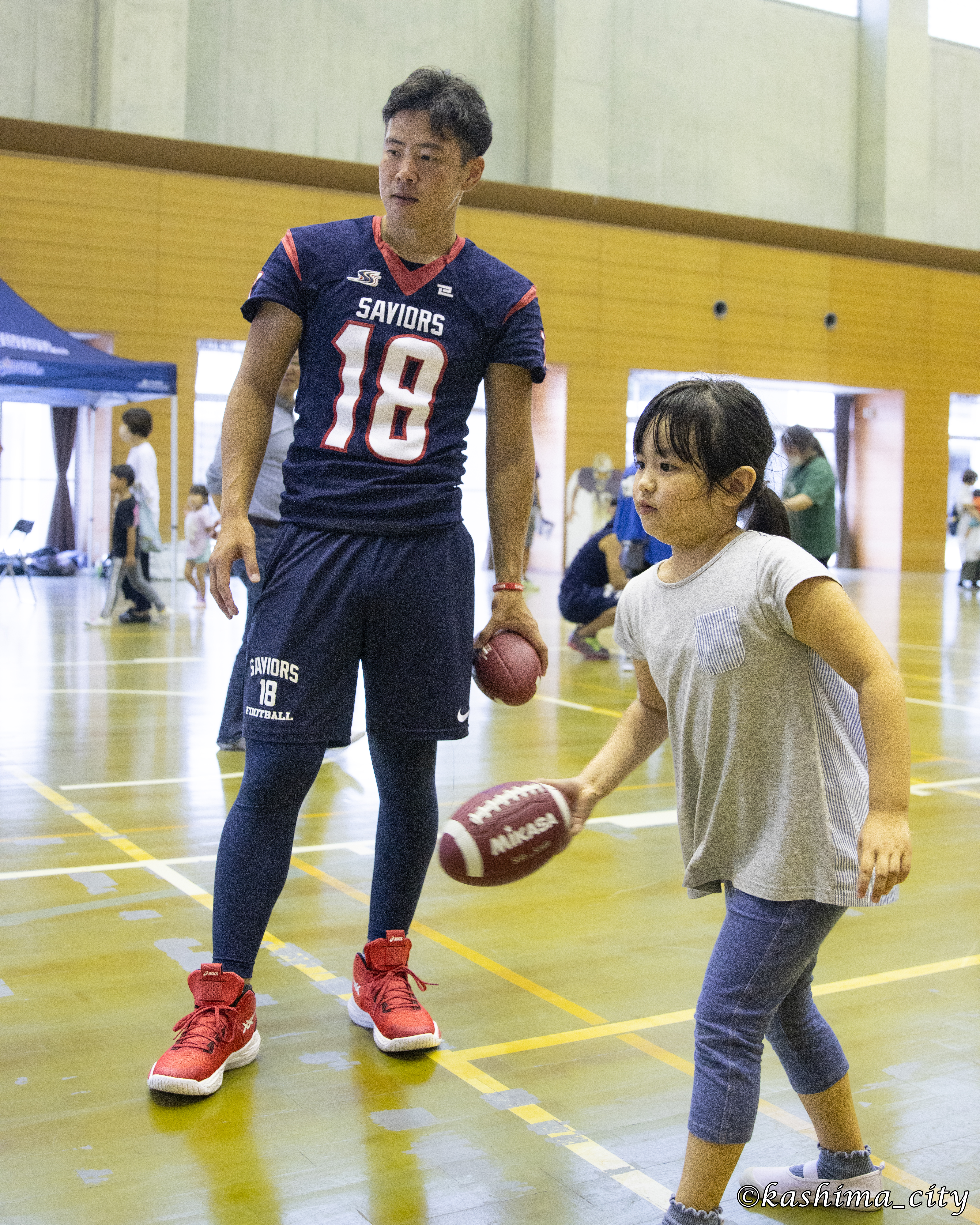 アメリカンフットボール体験をする女子小学生