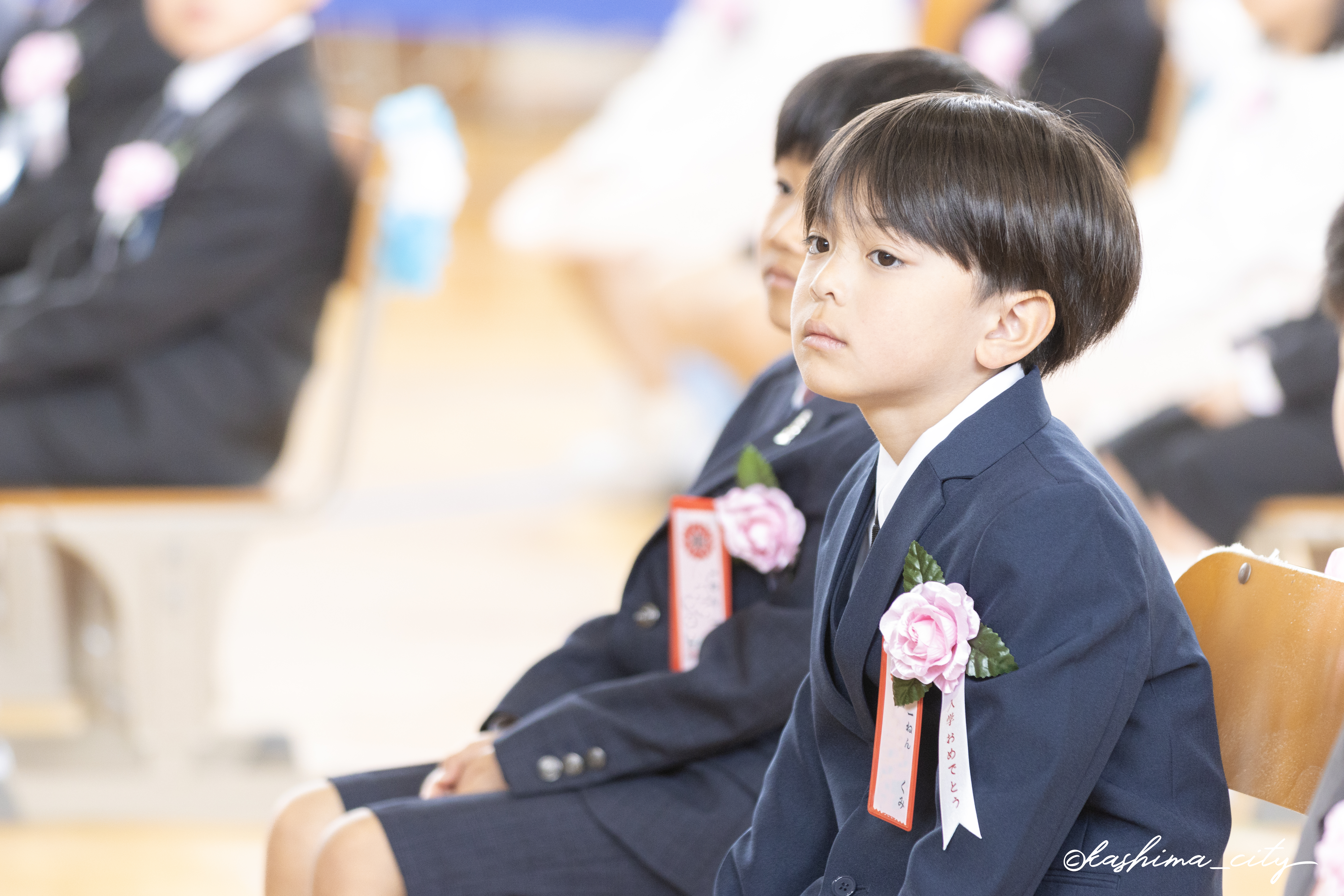 式中、椅子に座って話を聞く男子児童の様子