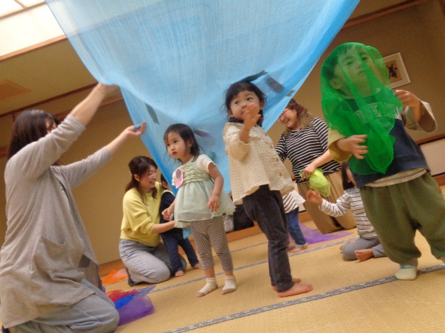 スカーフを空に見立てて遊ぶ子どもたち