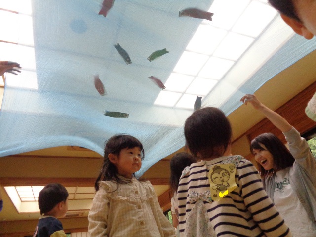 スカーフに鯉のぼりが張り付いていて見上げる子どもたち