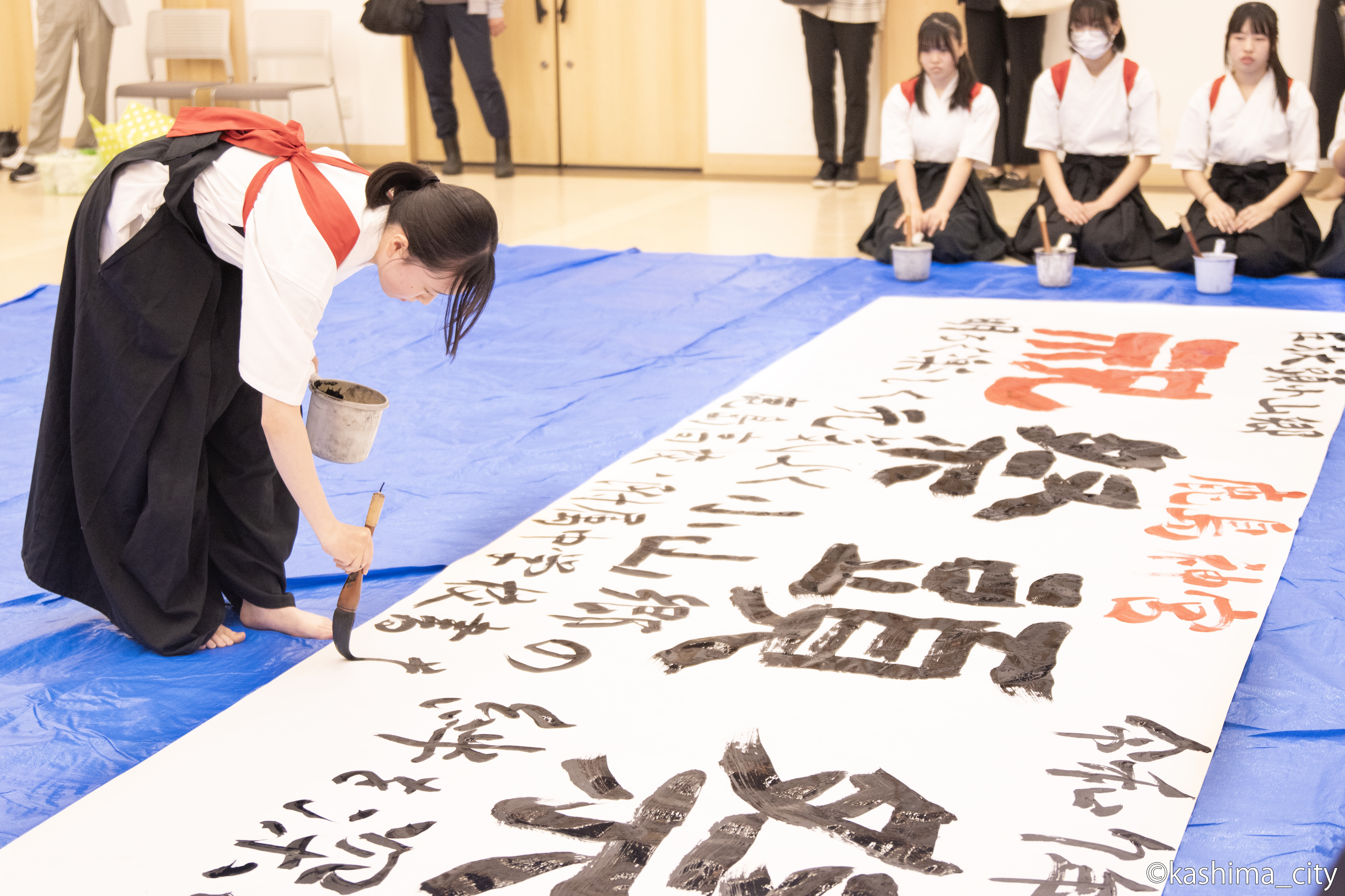 横断幕に学校名を書いている様子