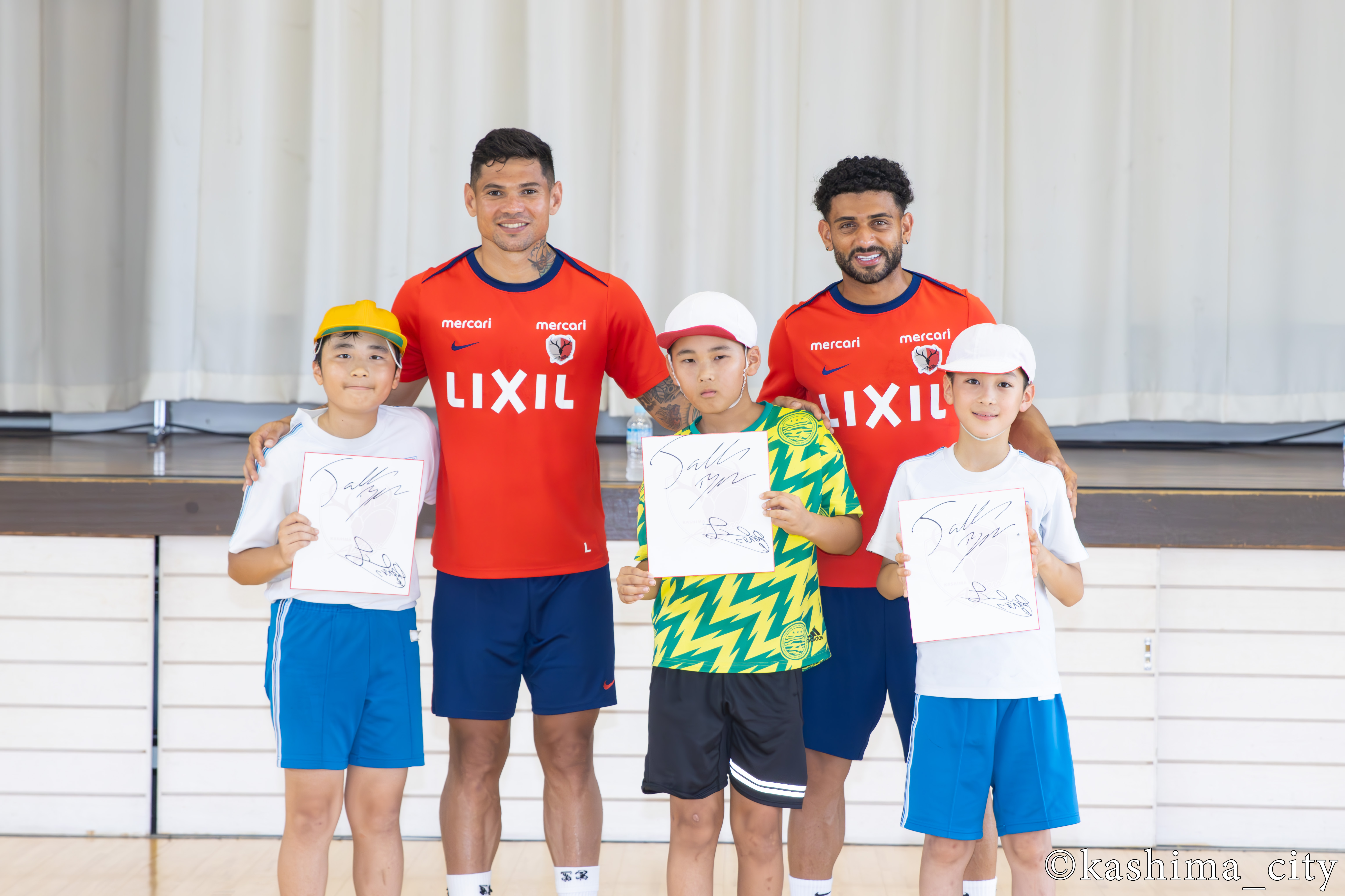 レオ セアラ選手、ターレス選手と写真を撮る児童たち