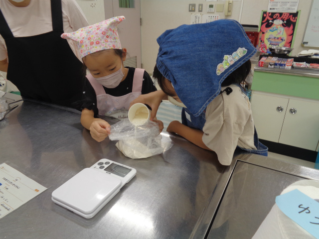 パン生地の材料を計る子どもたち