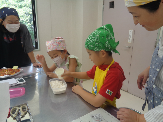 強力粉に水を入れる子ども