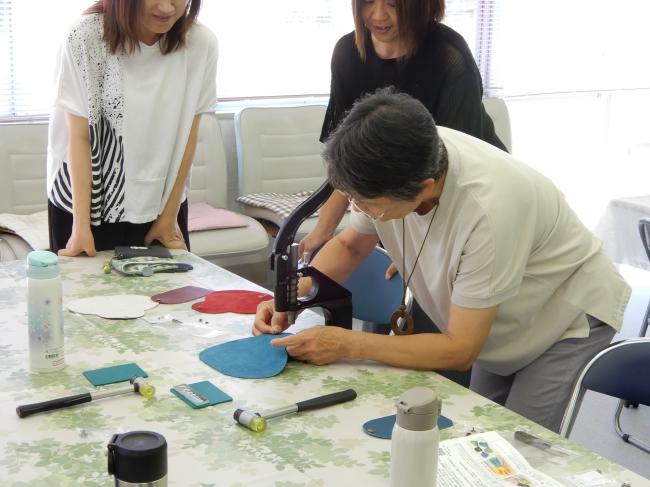 道具を使ってアコーディオンポーチに金具を付けています。