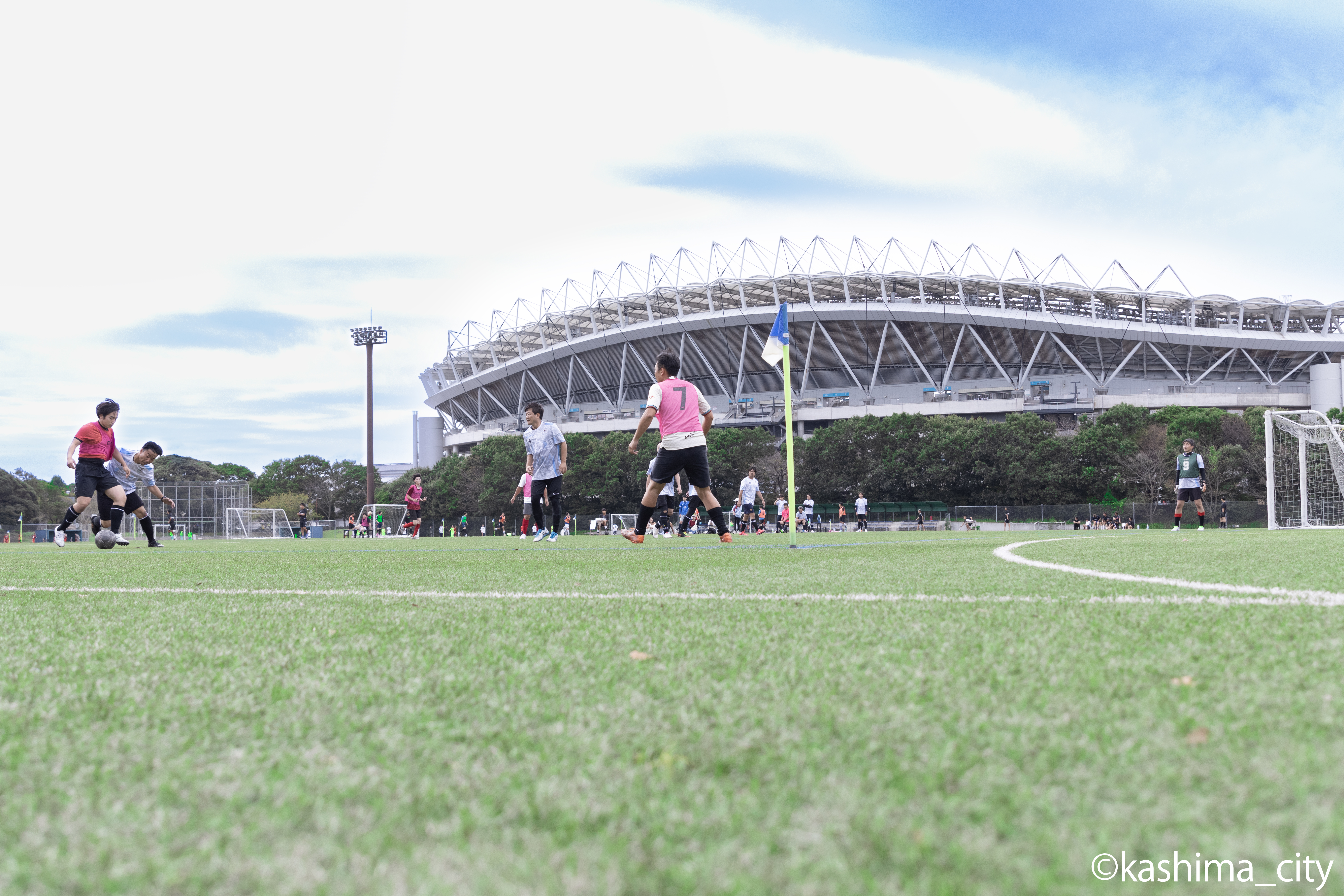 カシマスタジアムをバックにサッカーをする皆さんの様子