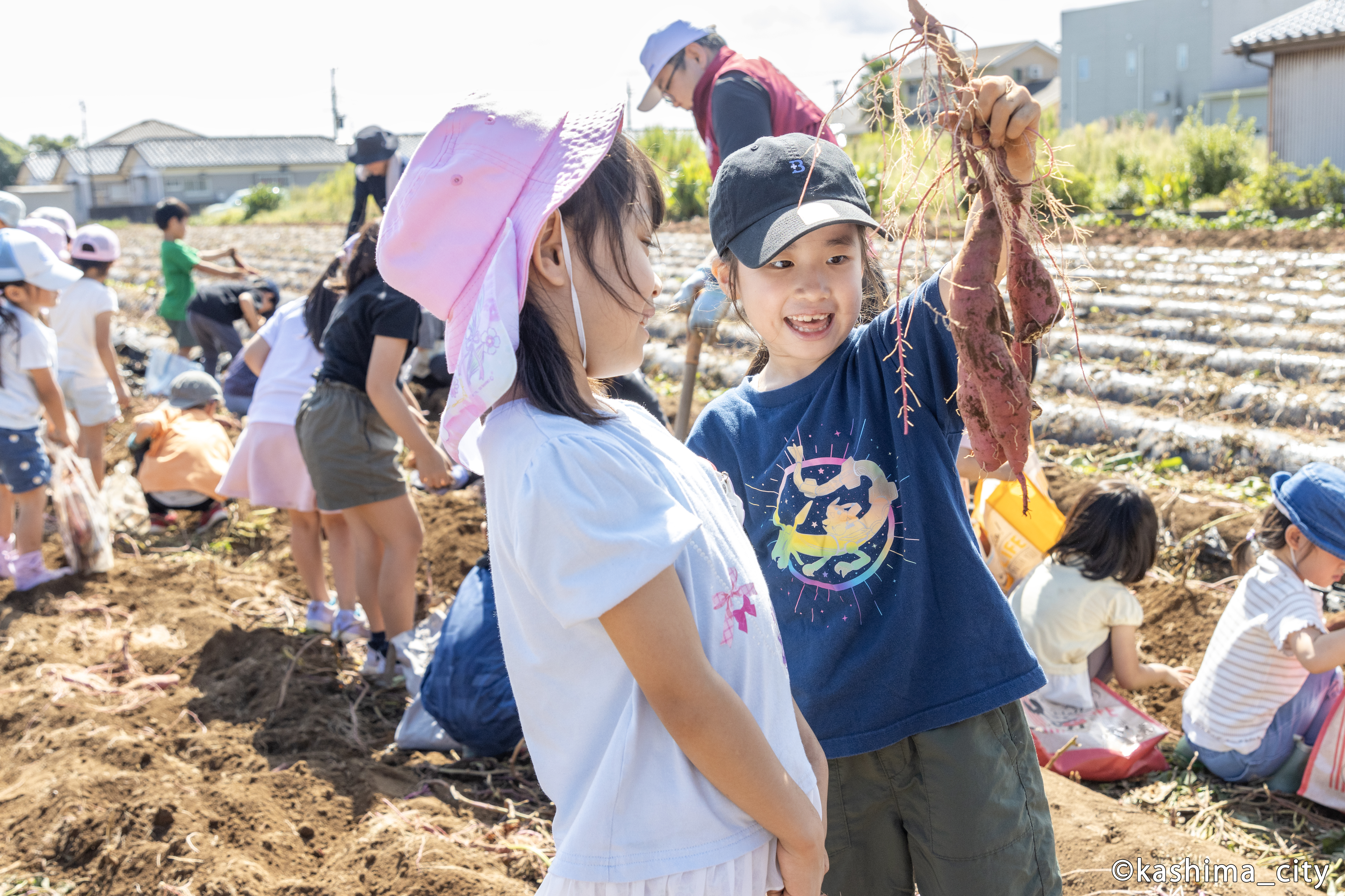 大きなサツマイモを友だちに見せる様子