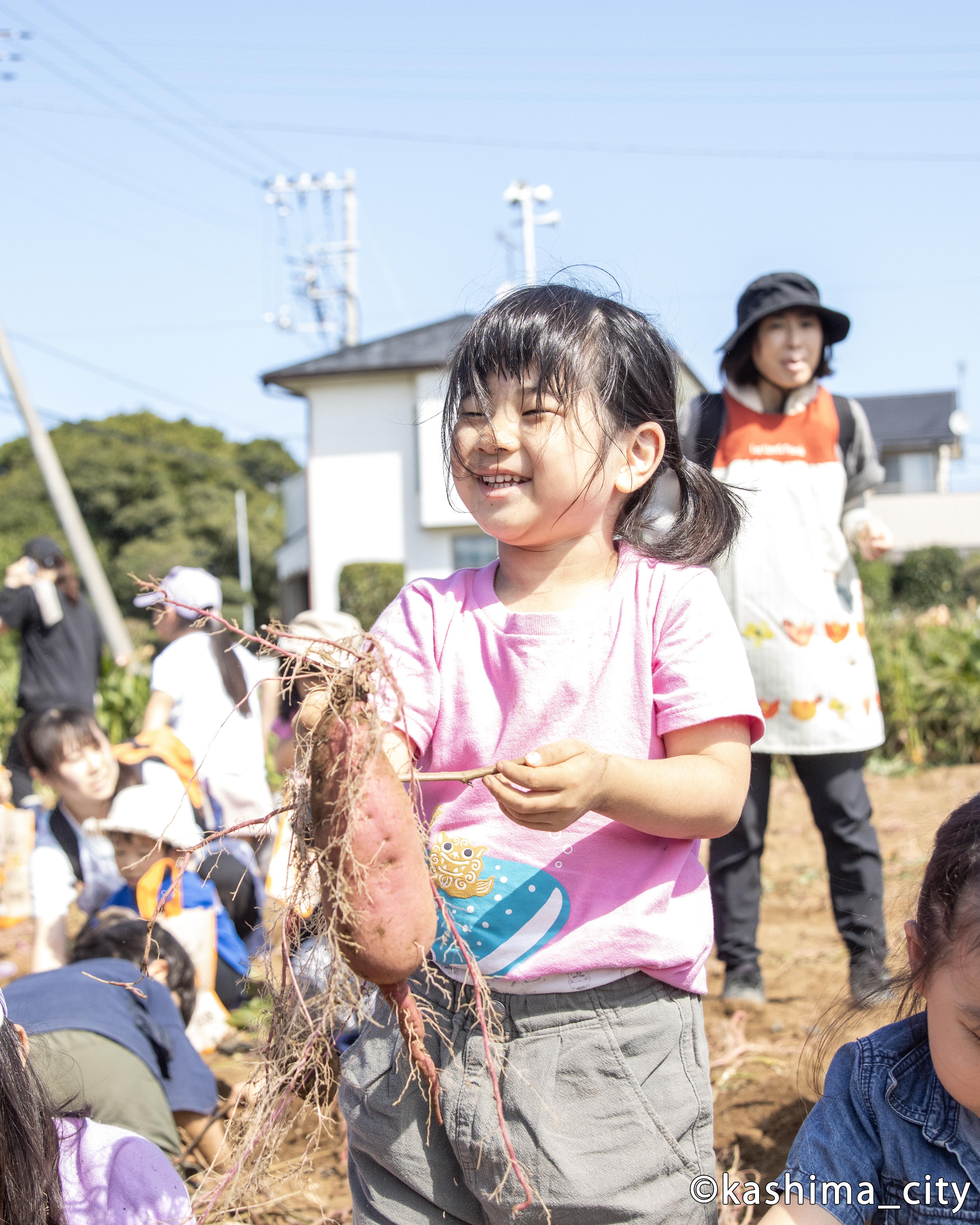 大きなサツマイモを掘り出して笑顔の様子