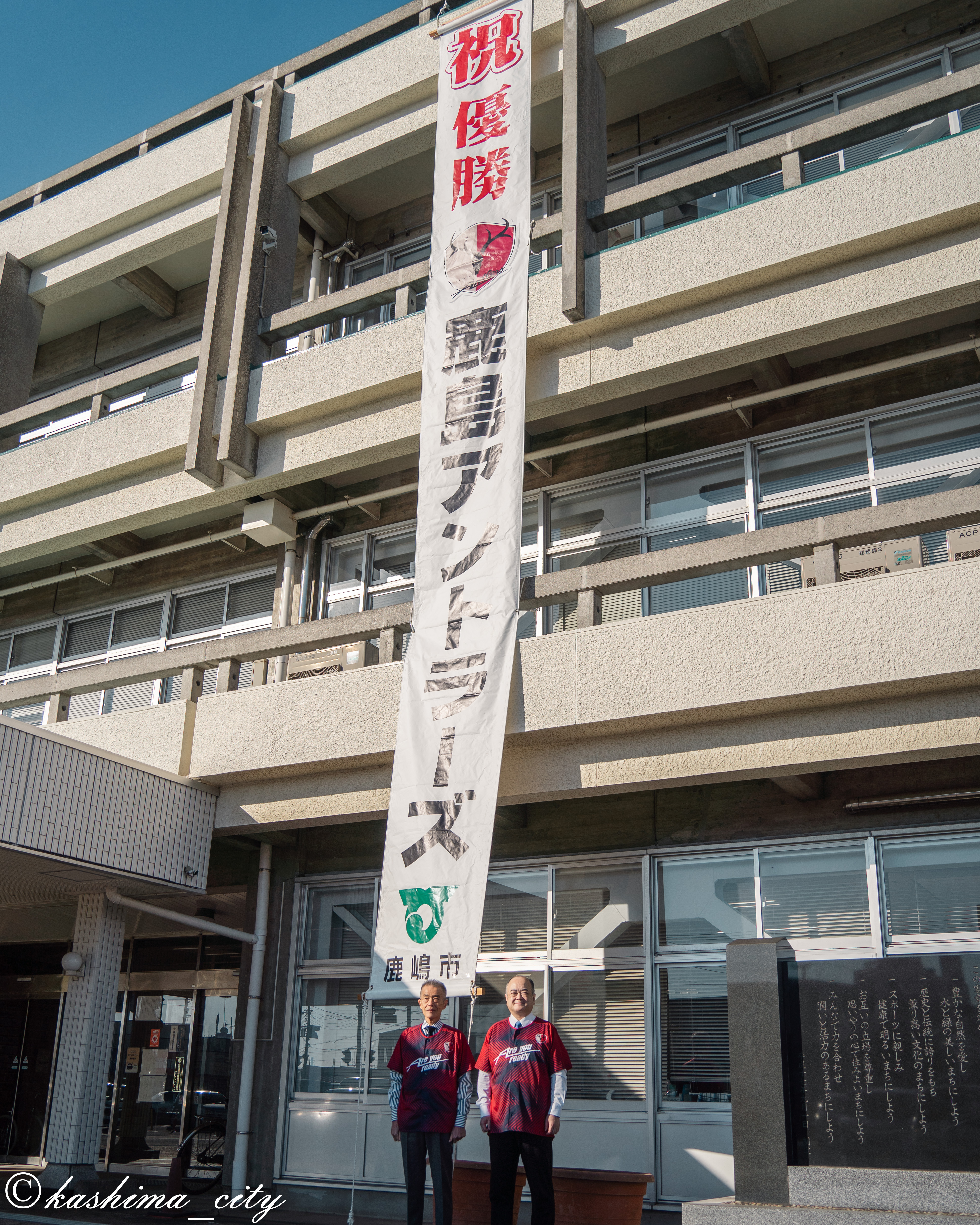 アントラーズ優勝の懸垂幕の前に立つ市長と副市長