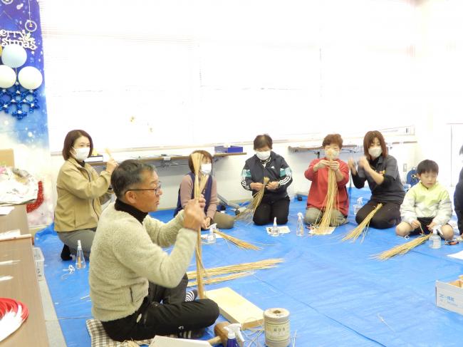 ワラの高さをそろえてしめ縄作りに挑戦する様子