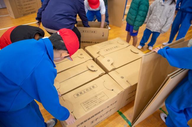 段ボールベッドを設置している児童の写真