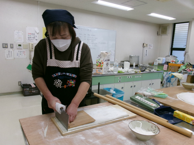 伸ばしたそば粉を切る参加者