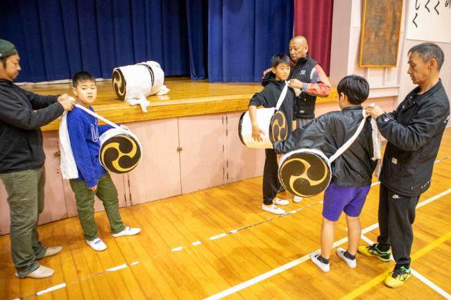 児童に太鼓を担がせている写真
