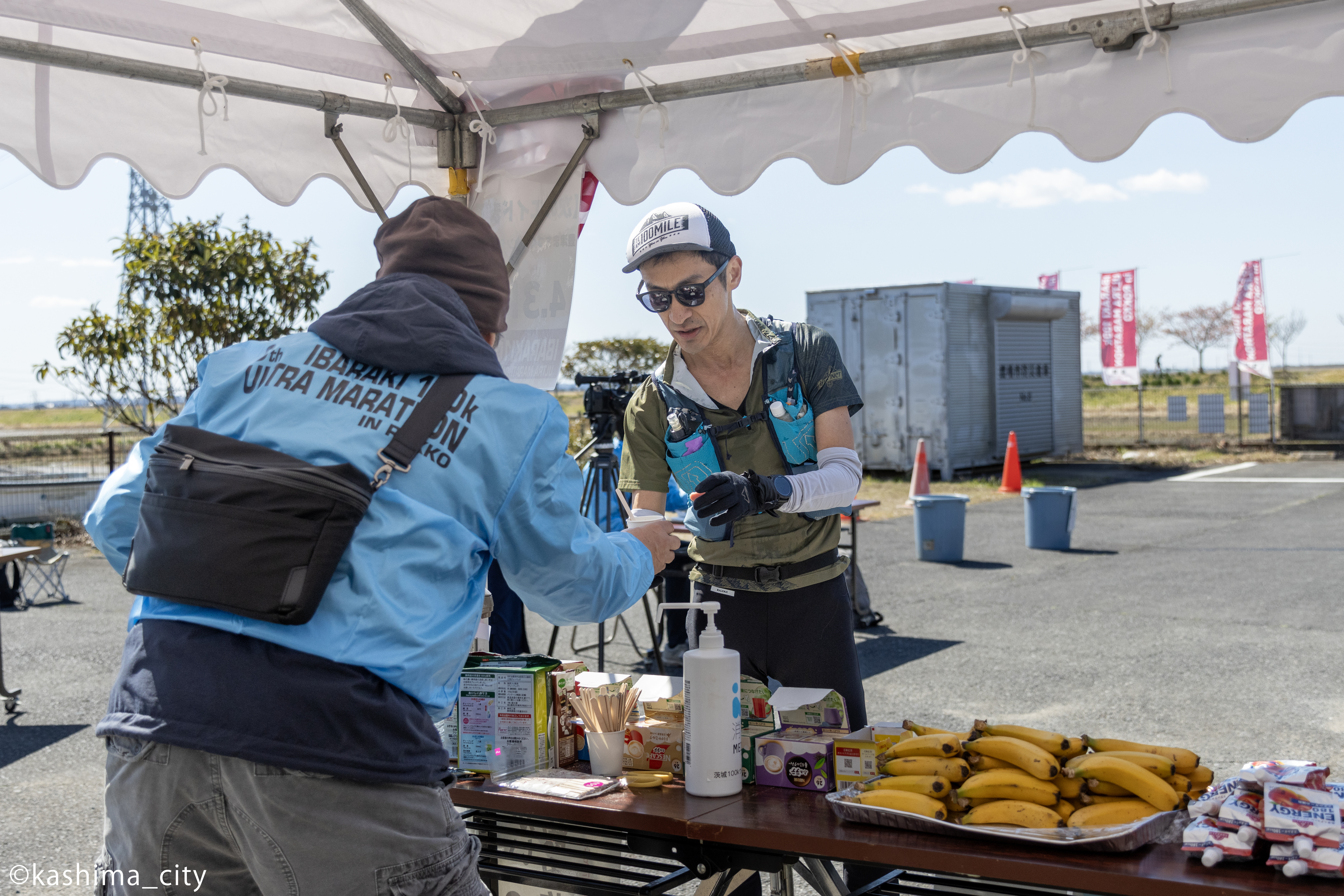 エイドステーションで飲みものを受取る男性