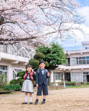 桜の下で笑って写る新入生