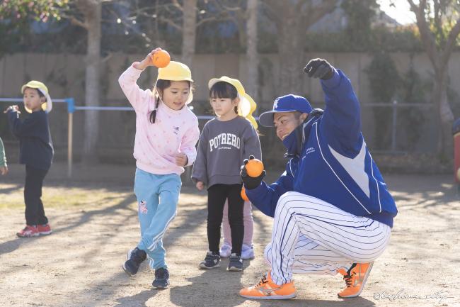 投球練習をする園児と選手
