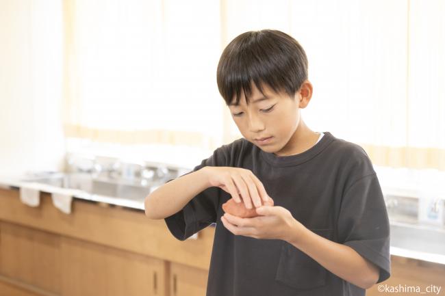 男子児童が真剣な表情で土器に高さを出していく様子