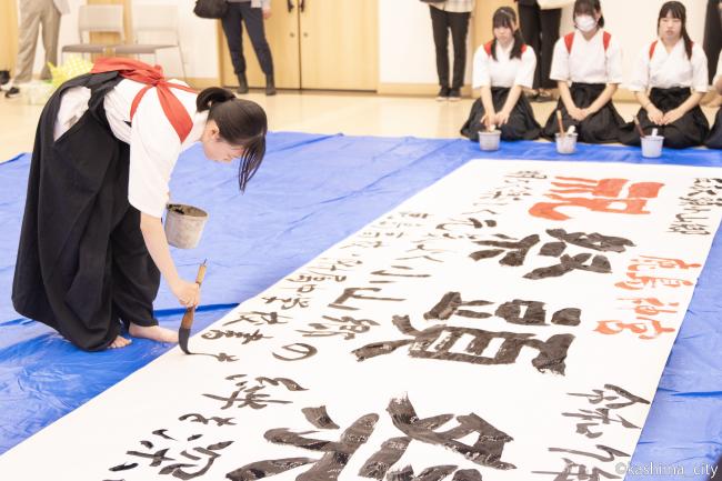 横断幕に学校名を書いている様子
