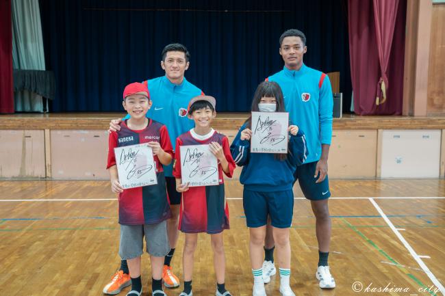 植田選手、ウデンバ選手からサイン色紙を贈呈された児童たち