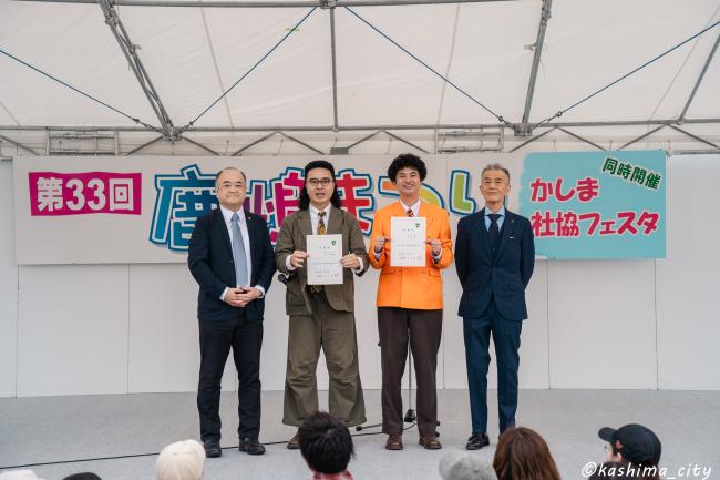 委嘱状を手にするカナメストーンと鹿嶋市長、副市長